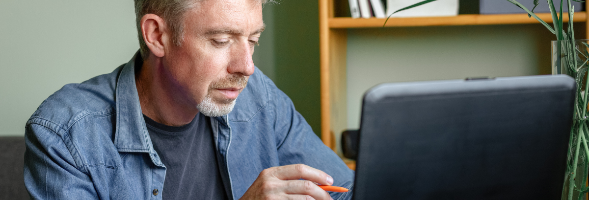 man looking over his computer and tablet