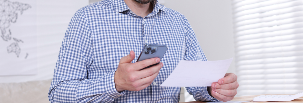 man looking at phone and paper